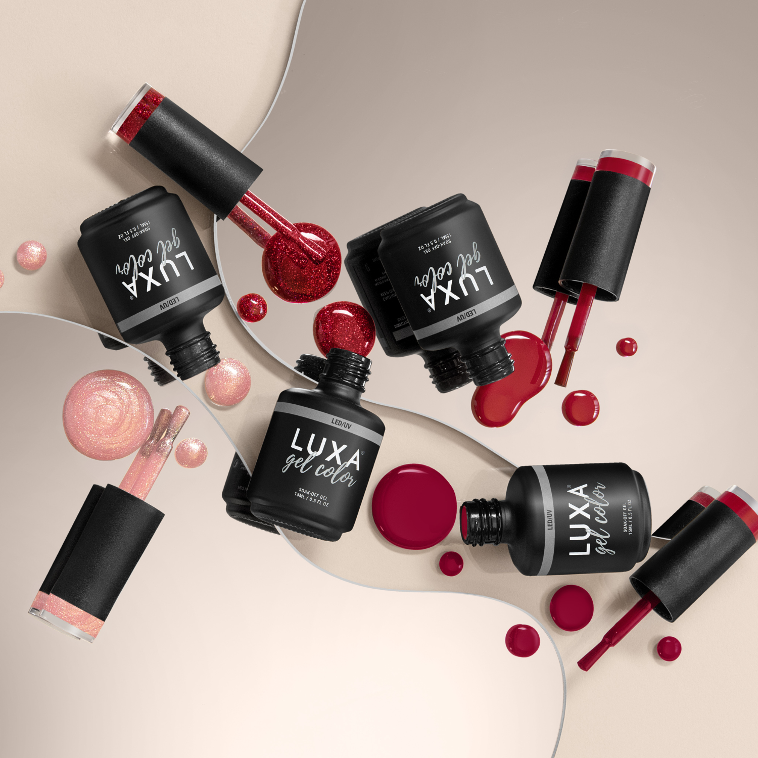 Flat lay of LUXA gel color bottles showcasing spilled red and pink gel polish and brushes on a beige mirrored background