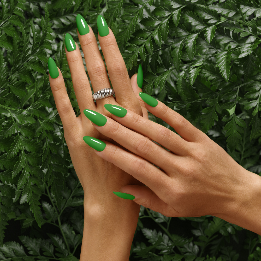 Overhead view of hands with almond-shaped nails in glossy Fresh Out of Ferns green gel polish on fern background