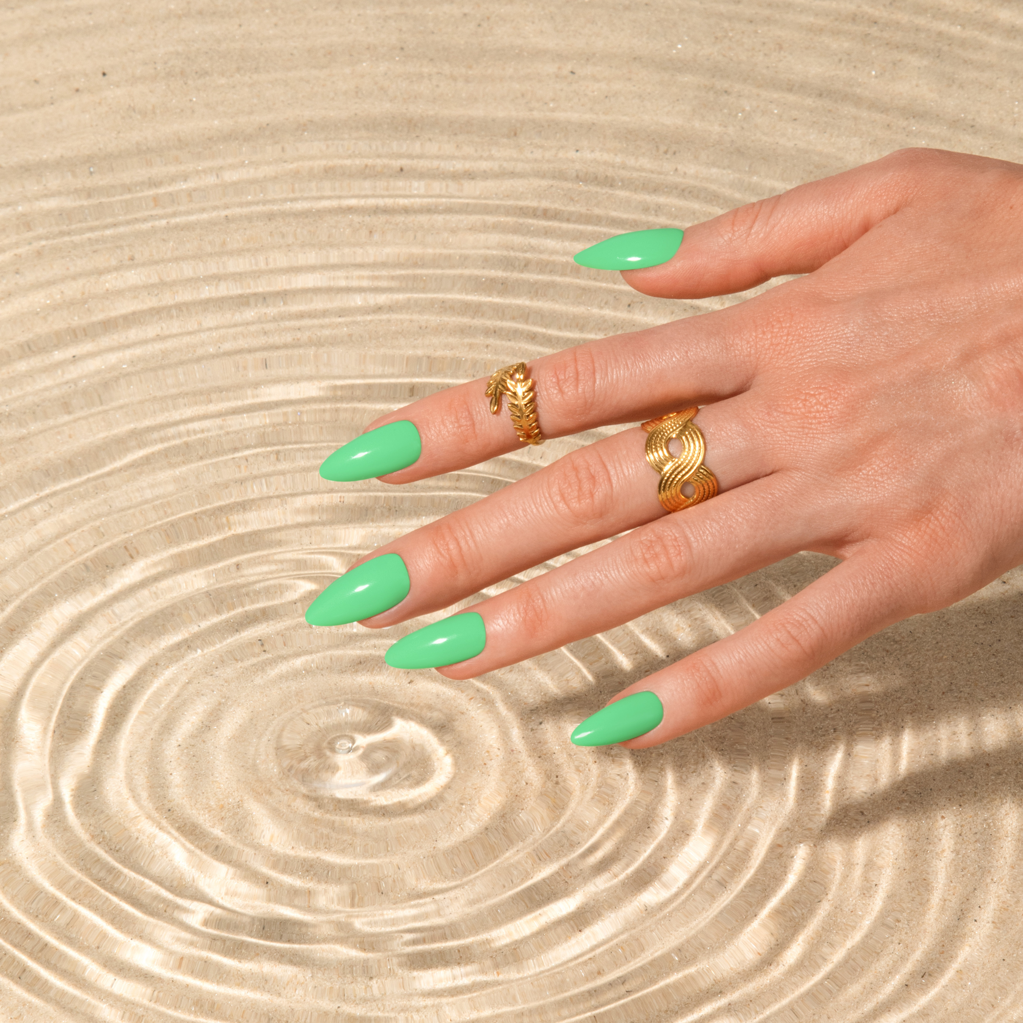 Hand displaying bright green gel nails over a textured glass dish